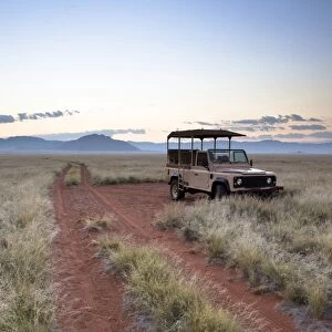 Land rover game vehicle parked by sand road at sunrise, Namib Rand game reserve, Namib Naukluft Park, Namibia, Africa
