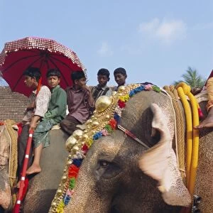 Mahoot and boys on decorated elephants at a roadside festival