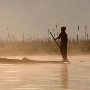 Man rowing his little rowing boat at sunrise on Inle Lake, Shan States, Myanmar, Asia