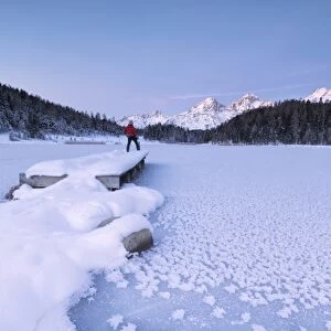 Man standing on the shore of frozen lake, Lej da Staz, St. Moritz, Engadine, Canton of Graubunden