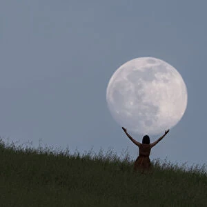 Full moon portrait at blue hour with a girl holding the moon above her head, Emilia Romagna, Italy, Europe