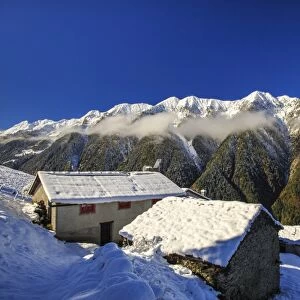 Mountain houses framed by snowy peaks, San Salvatore, Livrio Valley, Orobie Alps