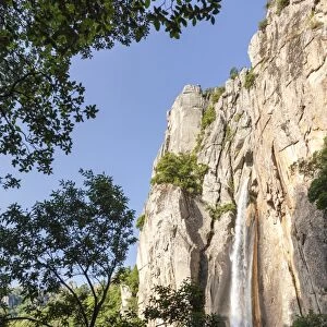 The Piscia di Gallo waterfall surrounded by granite rocks and green woods, Zonza