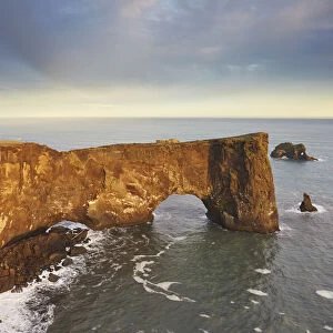 A rock arch on Dyrholaey Island seen in sunset sunlight, near Vik, south coast of Iceland, Polar Regions