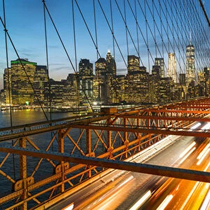Rush hour traffic at night on Brooklyn Bridge and Manhattan skyline beyond, New York City