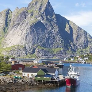 Ship in the blue sea frames the fishing village and the rocky peaks, Reine, Moskenesoya