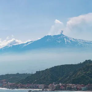 Small boat passing the awe inspiring Mount Etna, UNESCO World Heritage Site