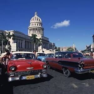 Street scene of old American automobiles used as taxis parked near the Capitolio Building in Central Havana, Cuba, West Indies