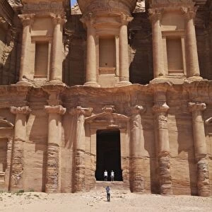 Tourists being photographed at the facade of the Monastery carved into the red rock at Petra, UNESCO World Heritage Site, Jordan, Middle East
