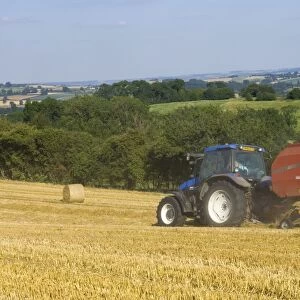 Tractor collecting hay bales at harvest time, seen from the Cotswolds Way footpath