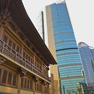 Traditional Chinese wooden architecture next to modern Chinese glass and steel buildings