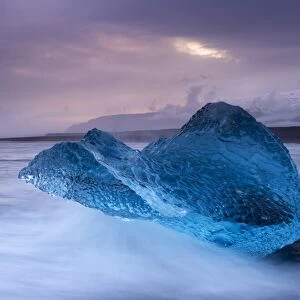 Translucent blue iceberg washed ashore on Breidamerkursandur black sands