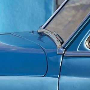 Detail of vintage blue American car against painted blue wall, Cienfuegos, Cuba, West Indies, Central America