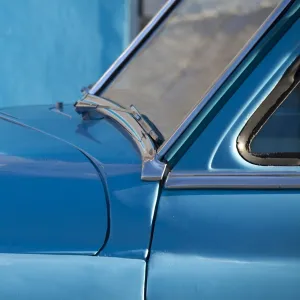 Detail of vintage blue American car against painted blue wall, Cienfuegos, Cuba, West Indies, Central America