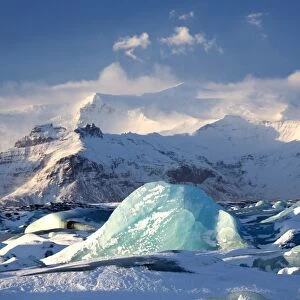Winter view over frozen Jokulsarlon Glacier Lagoon showing blue icebergs covered in snow