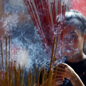 Woman praying with burning incense sticks, Ong Bon Pagoda, Taoist Temple