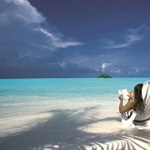 Woman reading a book on the beach, Maldives, Indian Ocean, Asia