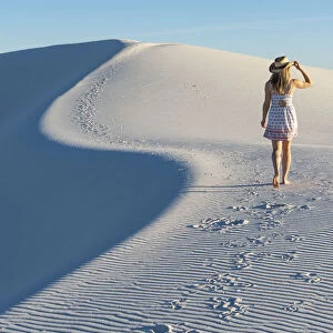 A woman walking along thes curve of a dunes ridge in White Sands National Park