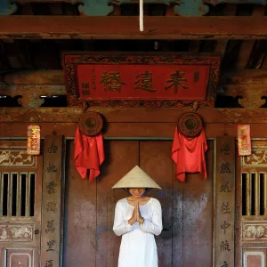 A young woman in a Non La conical hat and a traditional Ao Dai dress in the historical centre