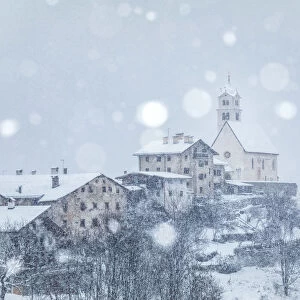 the ancient village of Colle Santa Lucia with the church on the hill under a snowfall