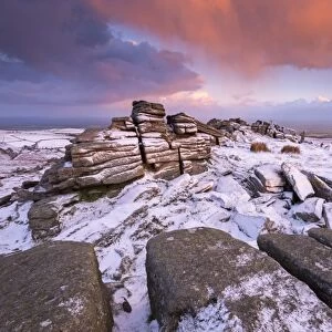 Colourful sunrise above snow covered moorland, Belstone Tor, Dartmoor, Devon, England