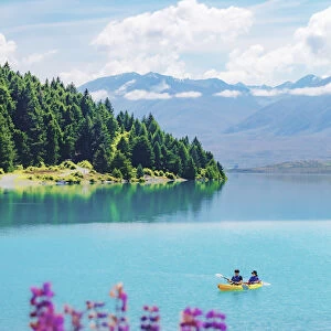 A coupld of asiasn riding the kayak in Tekapo lake on a sunny day with lupins in bloom