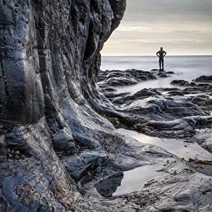 Lone figure standing on shoreline at Porth Ledden, Cape Cornwall, Cornwall, England, UK