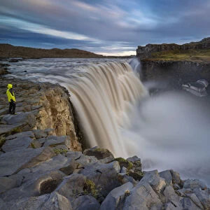 A man observes Dettifoss waterfall at its east side during midnight sun