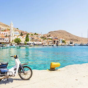 Motor cycle by the harbour and St Nicholas Church, Halki, Dodecanese Islands, Greece