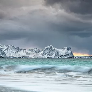 Storm clouds at sunset over snowcapped mountains and cold arctic sea, Bovaer beach, Skaland, Senja, Troms county, Norway