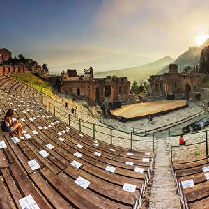 Taormina, Sicily. People sitting in the greek theater with the sun setting