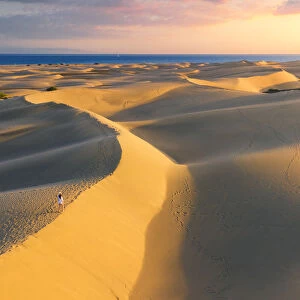 Tourist walking on sand dunes at sunset. Maspalomas, Las Palmas, Gran Canaria