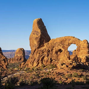 Tourists approaching Turret Arch against clear sky on sunny day, Arches National Park