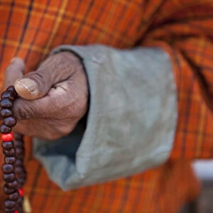 Wangdue, Bhutan. A man in a Gho with a closeup of Bhuddist prayer beads