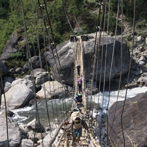 NEPAL, Annapurna Circuit Trek Crossing a sagging suspension bridge over the Khudi