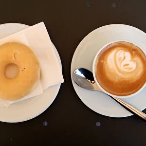 A coffee with milk and a donut are served in bakery in Vilassar de Dalt town