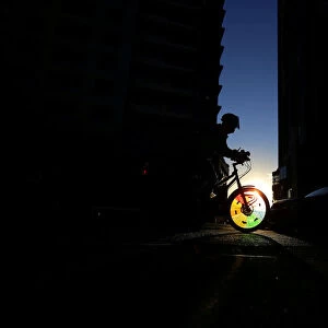 A cyclist rides into a shaft of light between two buildings in Sydneys business district