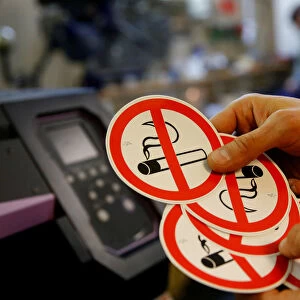 An employee shows no smoking signs in the Karas printing shop in Vienna