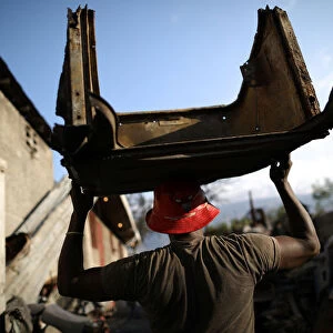 A man carries a piece of metal in a scrapyard in Port-au-Prince