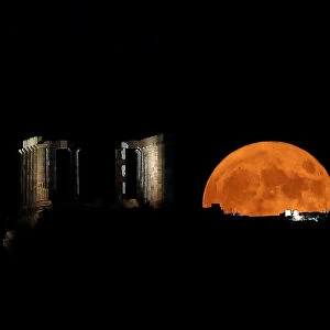 A full moon rises behind the Temple of Poseidon in Cape Sounion, near Athens