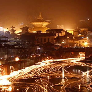 Oil lamps offered by devotees illuminate the Bagmati River flowing through the premises