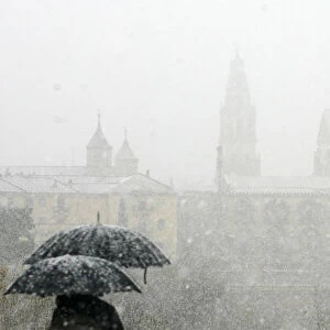 People stand with umbrellas in the snow, in Cordoba