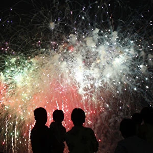 People watch fireworks explode during the Chofu city fireworks festival in Kawasaki