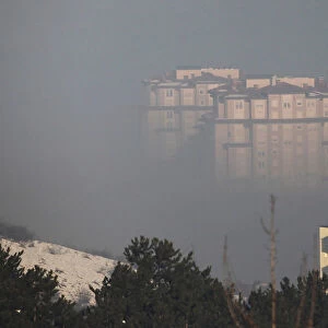 Residential buildings are seen amid morning smog in Pristina