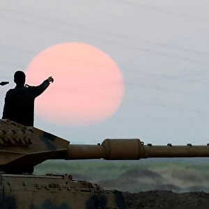 A Turkish soldier points as he stands on a tank during a military exercise near the