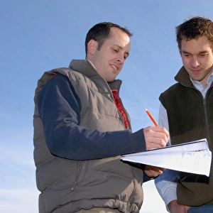 Agronomist and farmer working out field plan, England, October