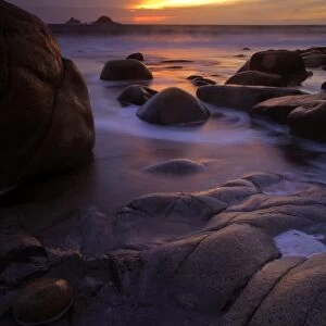View of eroded rock formations on beach at sunset, near Lands End, Cornwall, England