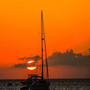 Seven Mile Beach, Grand Cayman. Sailboat and a boat with the orange sun setting behind