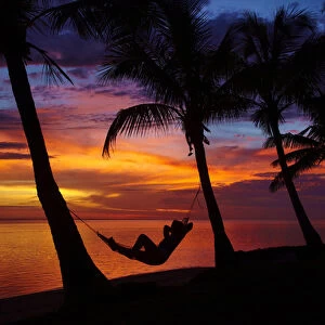 Woman in hammock, and palm trees at sunset, Coral Coast, Viti Levu, Fiji, South Pacific