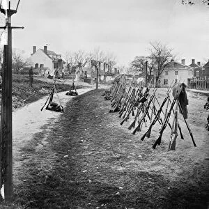 CIVIL WAR: STACKED RIFLES. Row of stacked Union rifles with houses in the background
